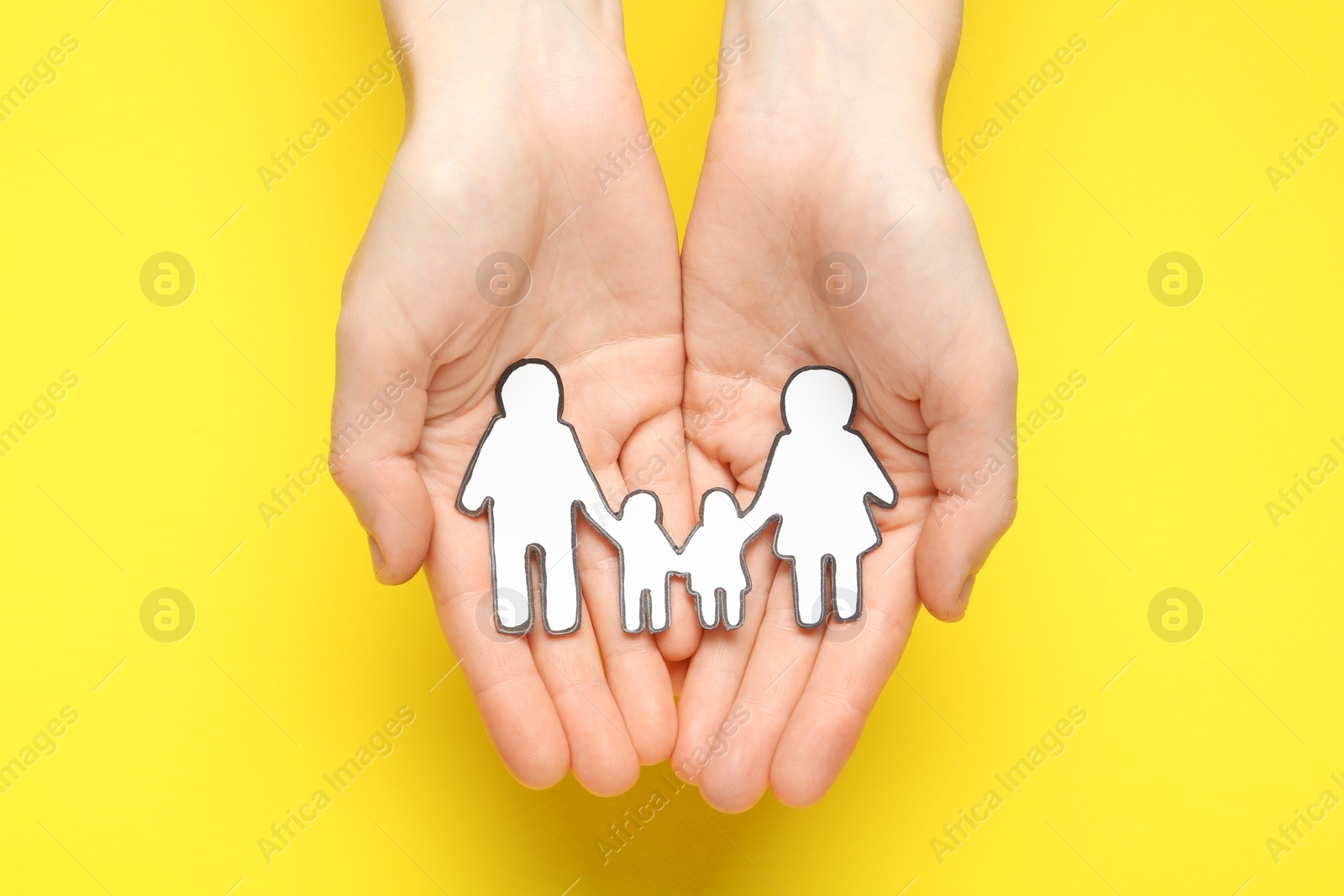 Photo of Woman holding paper family cutout on yellow  background, top view