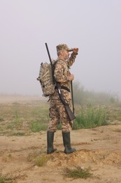 Man wearing camouflage with hunting rifle and backpack outdoors