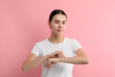 Photo of Woman with dry skin checking her arm on pink background