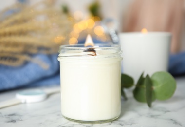 Photo of Burning candles with wooden wicks on white marble table