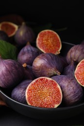 Photo of Bowl with fresh ripe purple figs on black table, closeup