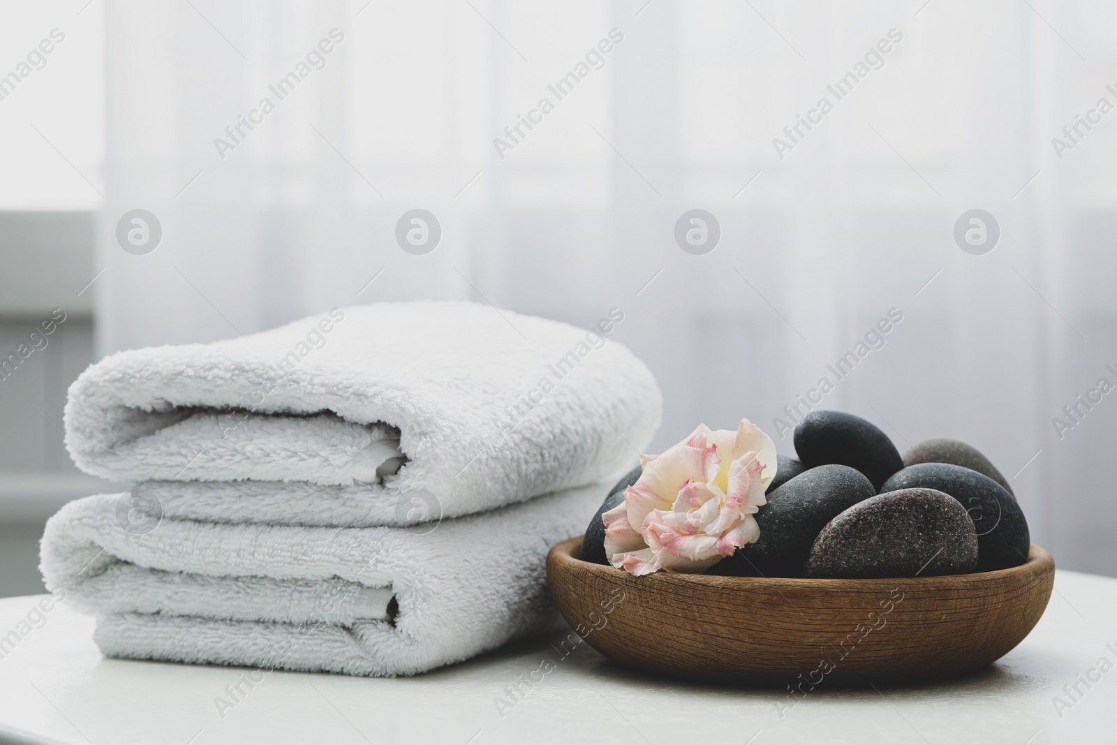 Photo of Spa stones and flowers on white table indoors