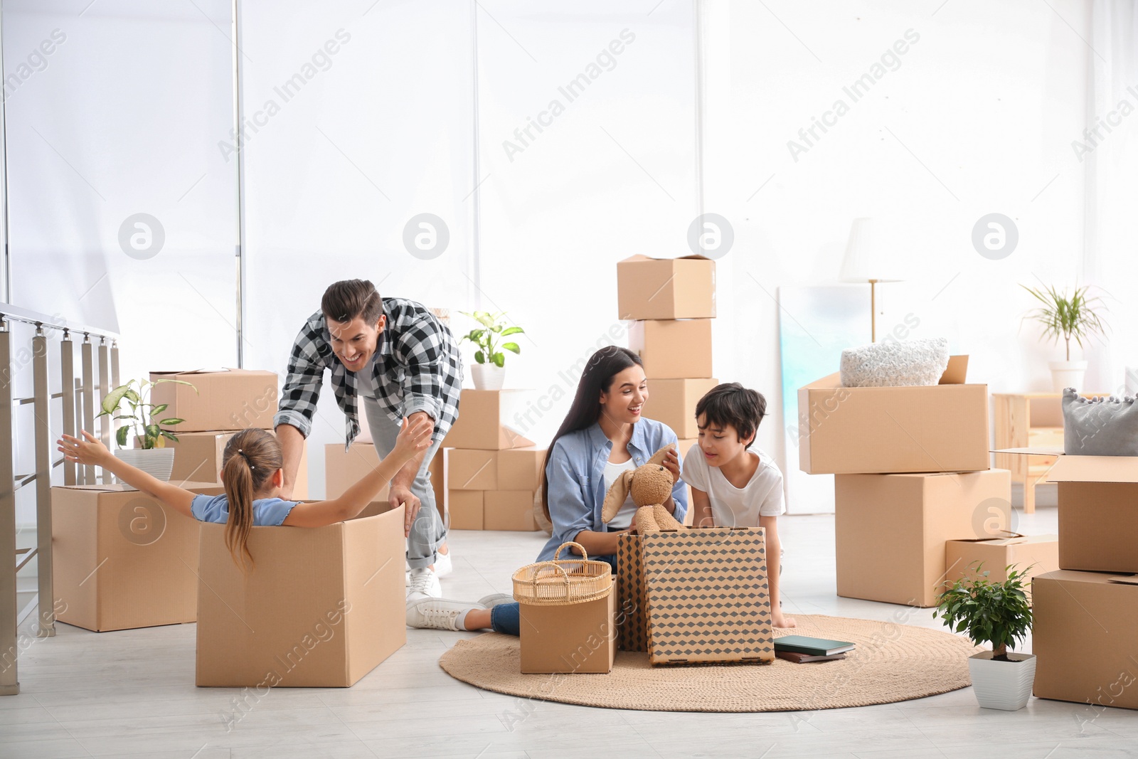 Photo of Happy family having fun while unpacking moving boxes at their new home