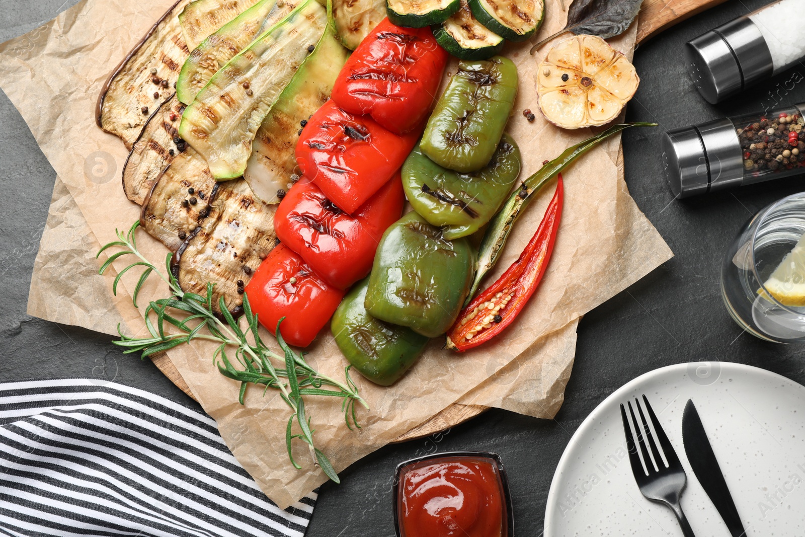 Photo of Delicious grilled vegetables served on dark grey table, flat lay
