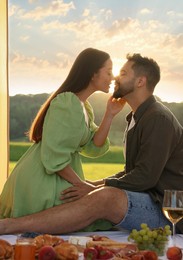 Photo of Romantic date. Beautiful couple kissing during picnic on sunny day