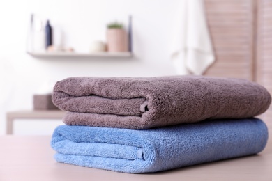 Stack of fresh towels on table in bathroom