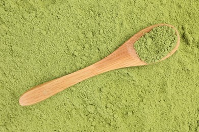 Wooden spoon on green matcha powder, top view