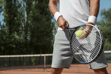 Sportsman playing tennis at court on sunny day, closeup