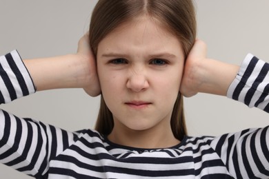 Photo of Hearing problem. Little girl suffering from ear pain on grey background
