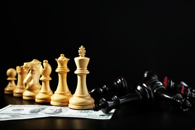 Photo of White chess pieces, black fallen ones and money against dark background. Business competition concept