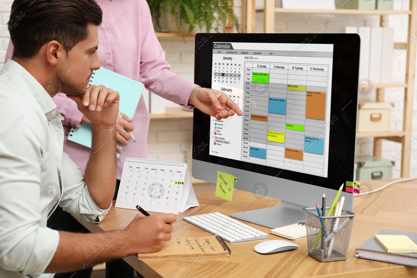 Photo of Colleagues working with calendar app on computer in office