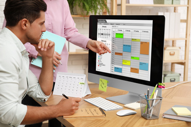 Colleagues working with calendar app on computer in office