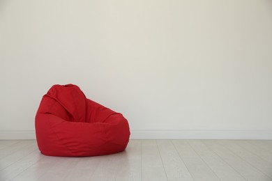 Photo of Red bean bag chair near light wall in room. Space for text