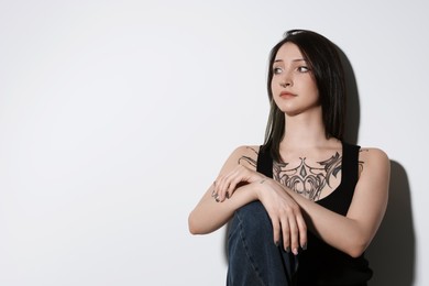 Portrait of beautiful tattooed woman on light background. Space for text