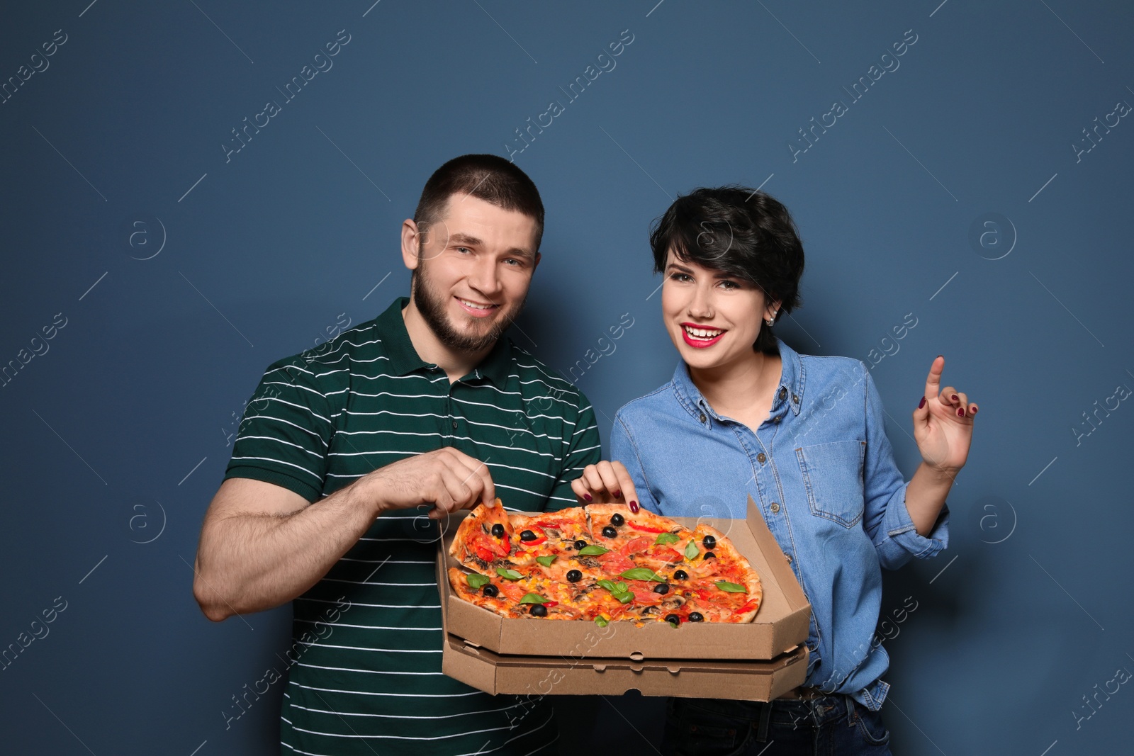 Photo of Attractive young couple with delicious pizza on color background