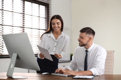 Photo of Woman helping her colleague with work in office