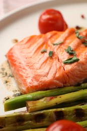 Photo of Tasty grilled salmon with spices and asparagus on plate, closeup