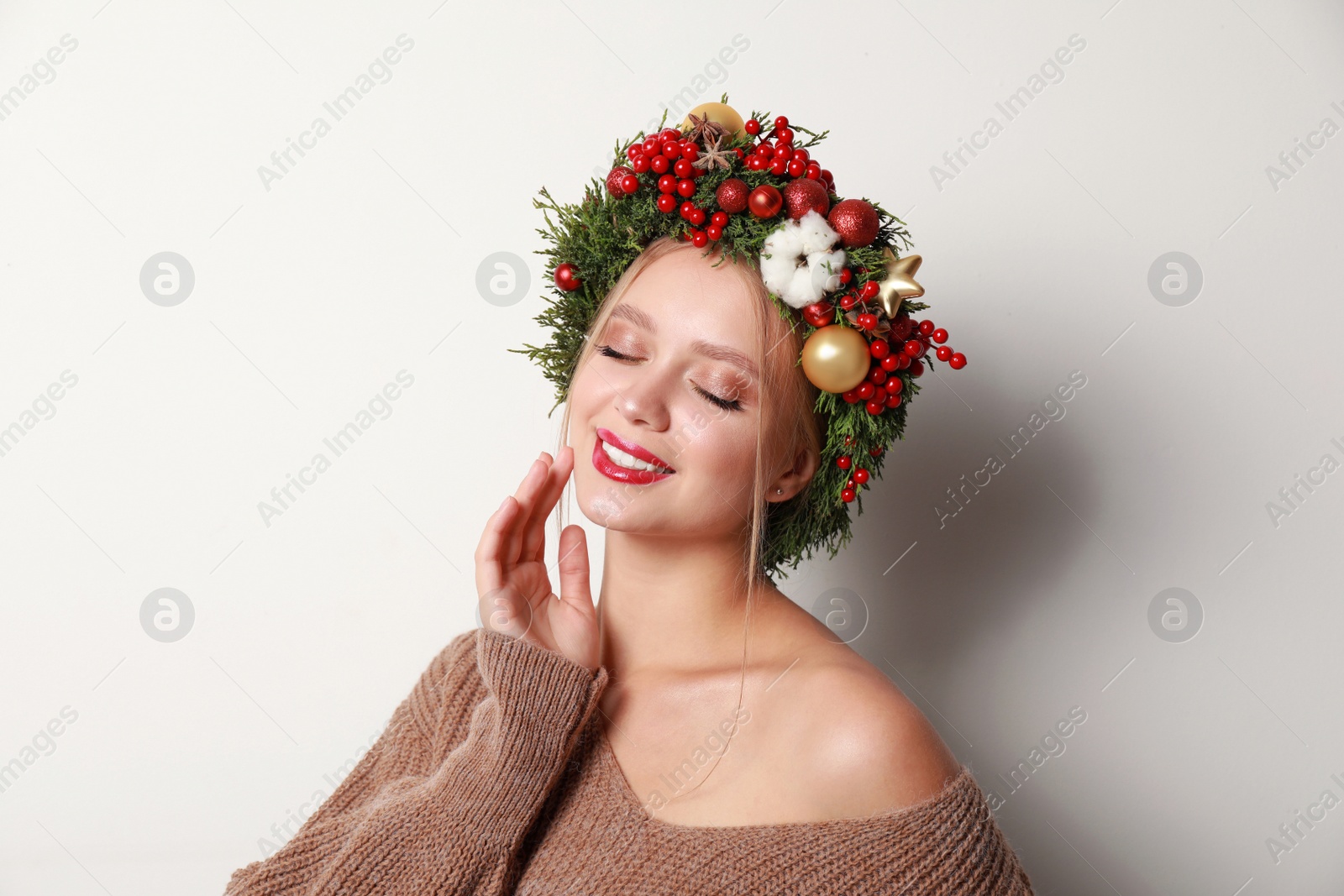 Photo of Beautiful young woman wearing Christmas wreath on white background