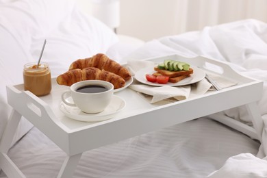 Photo of Good morning. Tray with tasty breakfast on bed at home