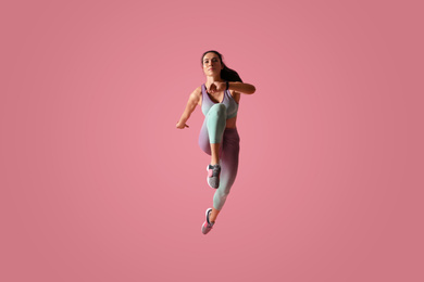 Photo of Athletic young woman running on pink background