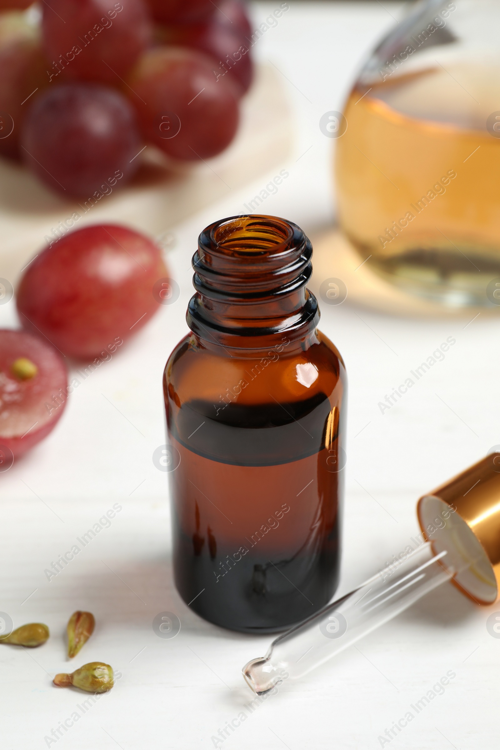 Photo of Natural grape seed oil on white wooden table. Organic cosmetic