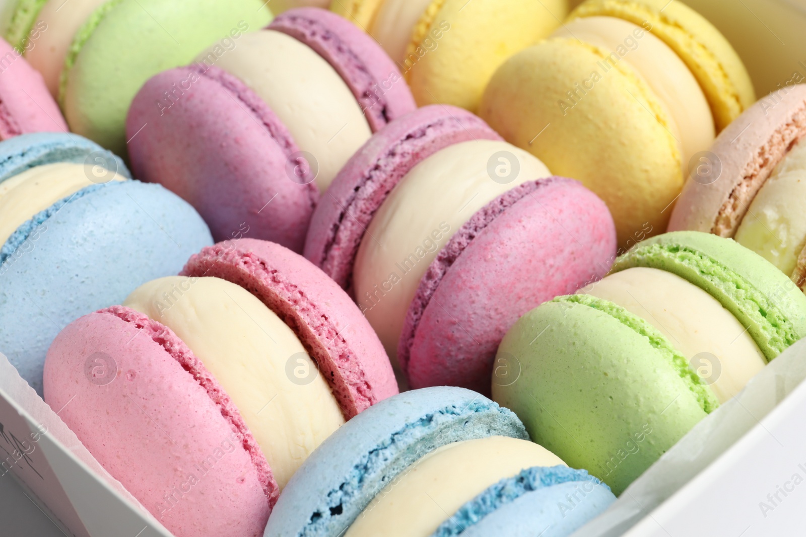 Photo of Many delicious colorful macarons in box, closeup