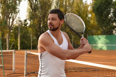 Photo of Handsome man playing tennis on court outdoors