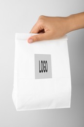 Image of Woman holding paper bag with logo on white background, closeup