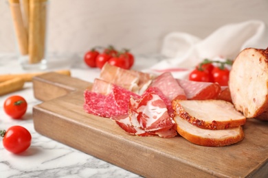 Photo of Cutting board with different meat delicacies on marble table