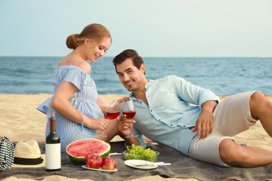 Beautiful young couple having picnic at sea beach