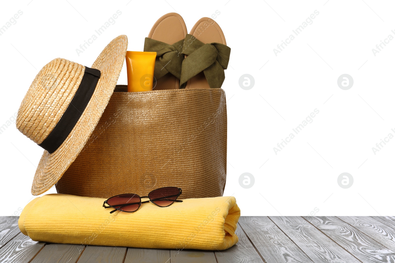 Photo of Stylish bag with beach accessories on grey wooden table against white background