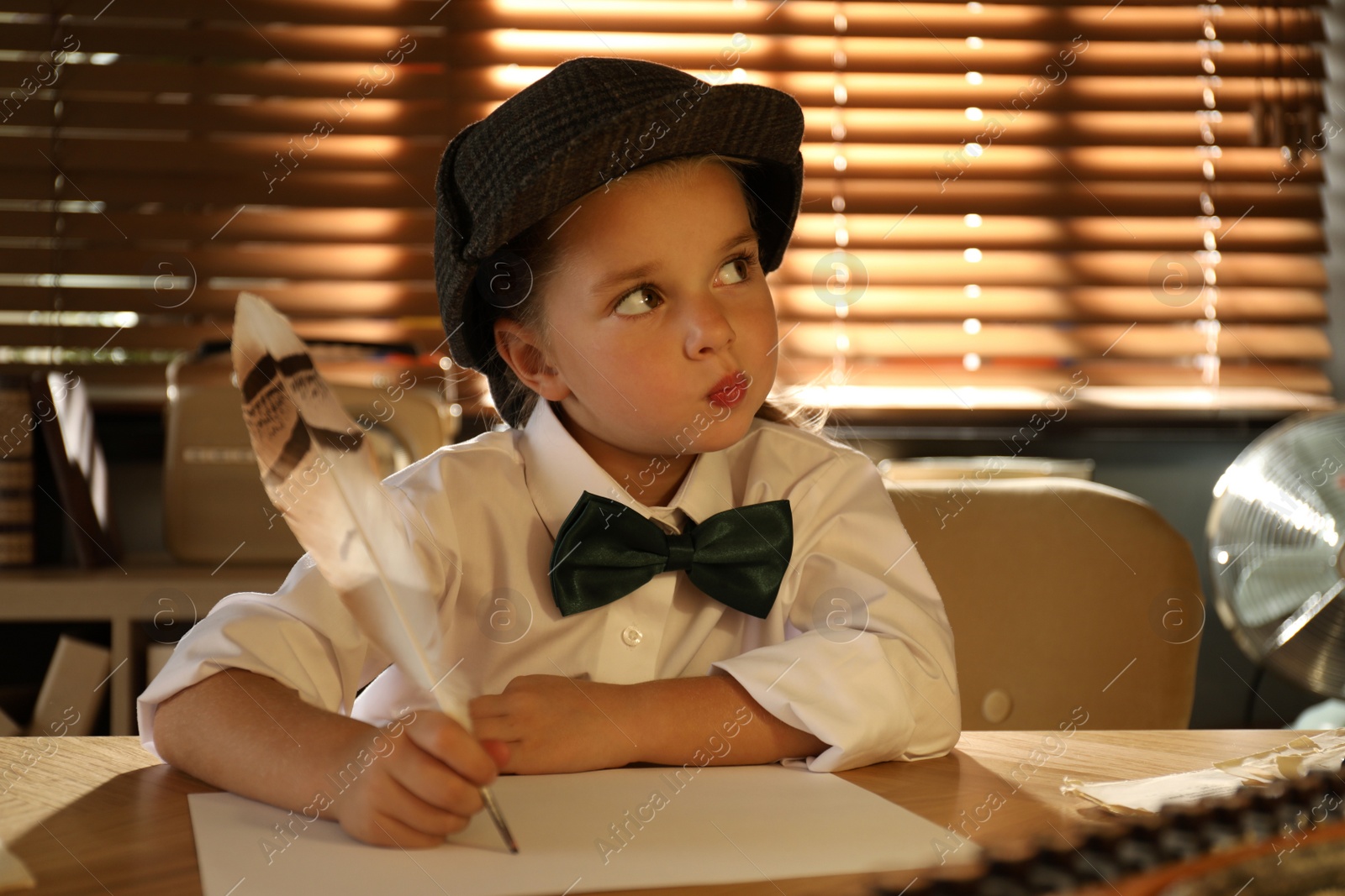 Photo of Cute little detective writing with feather at table in office