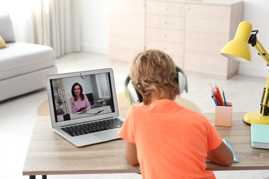 Photo of Little boy studying with teacher via video conference at home. Distance learning during COVID-19 pandemic