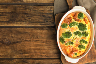 Photo of Tasty broccoli casserole in baking dish on wooden table, top view. Space for text
