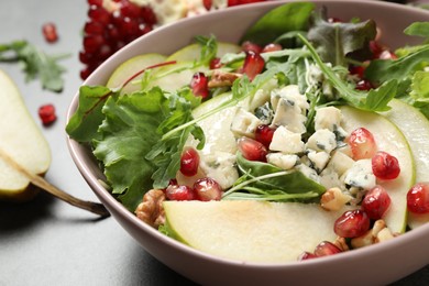 Photo of Tasty salad with pear slices and pomegranate seeds on table, closeup