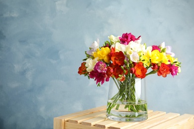 Photo of Bouquet of spring freesia flowers in vase on color background. Space for text