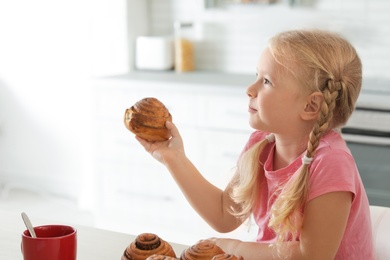 Little girl with freshly oven baked bun in kitchen