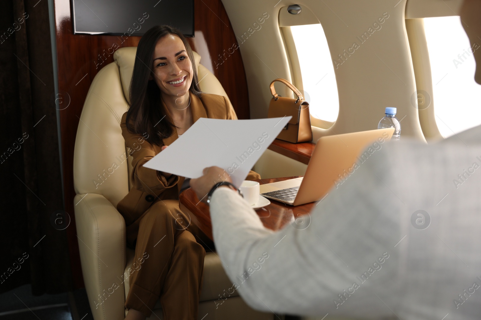 Photo of Man giving documents to woman in airplane during flight