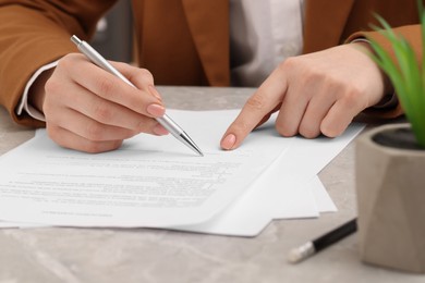 Woman signing document at table, closeup view