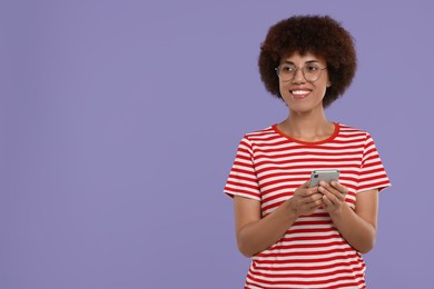 Photo of Happy young woman with smartphone on purple background. Space for text