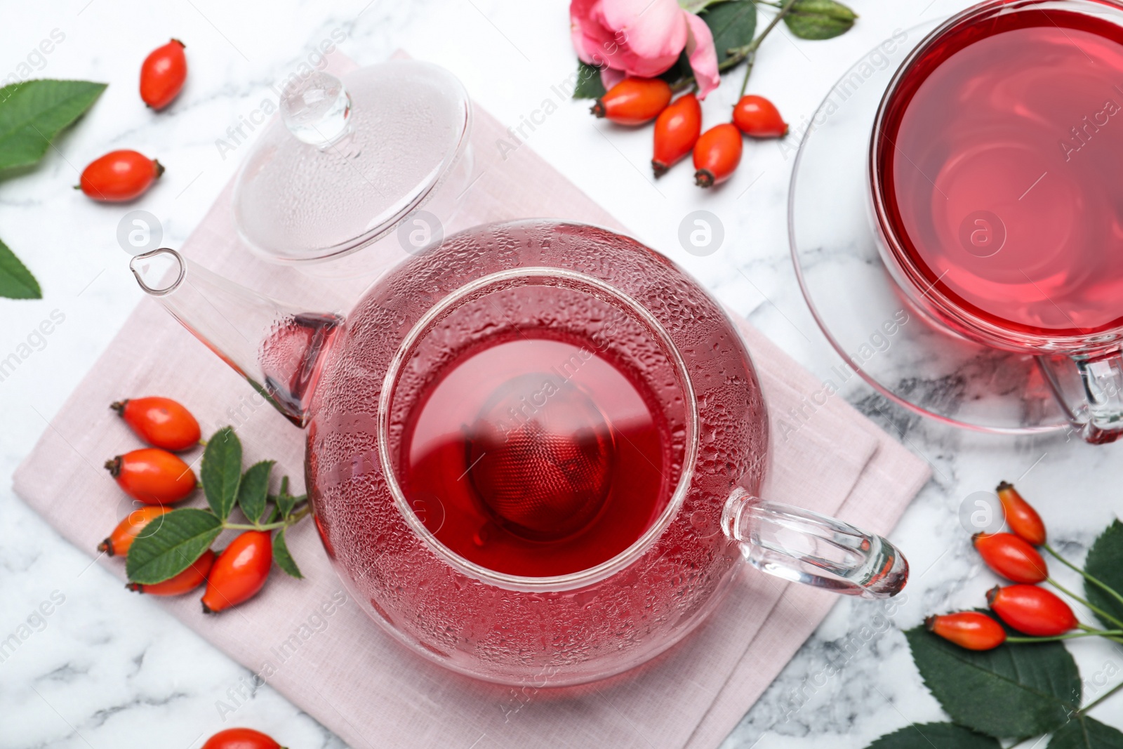 Photo of Fresh rose hip tea and berries on white marble table, flat lay