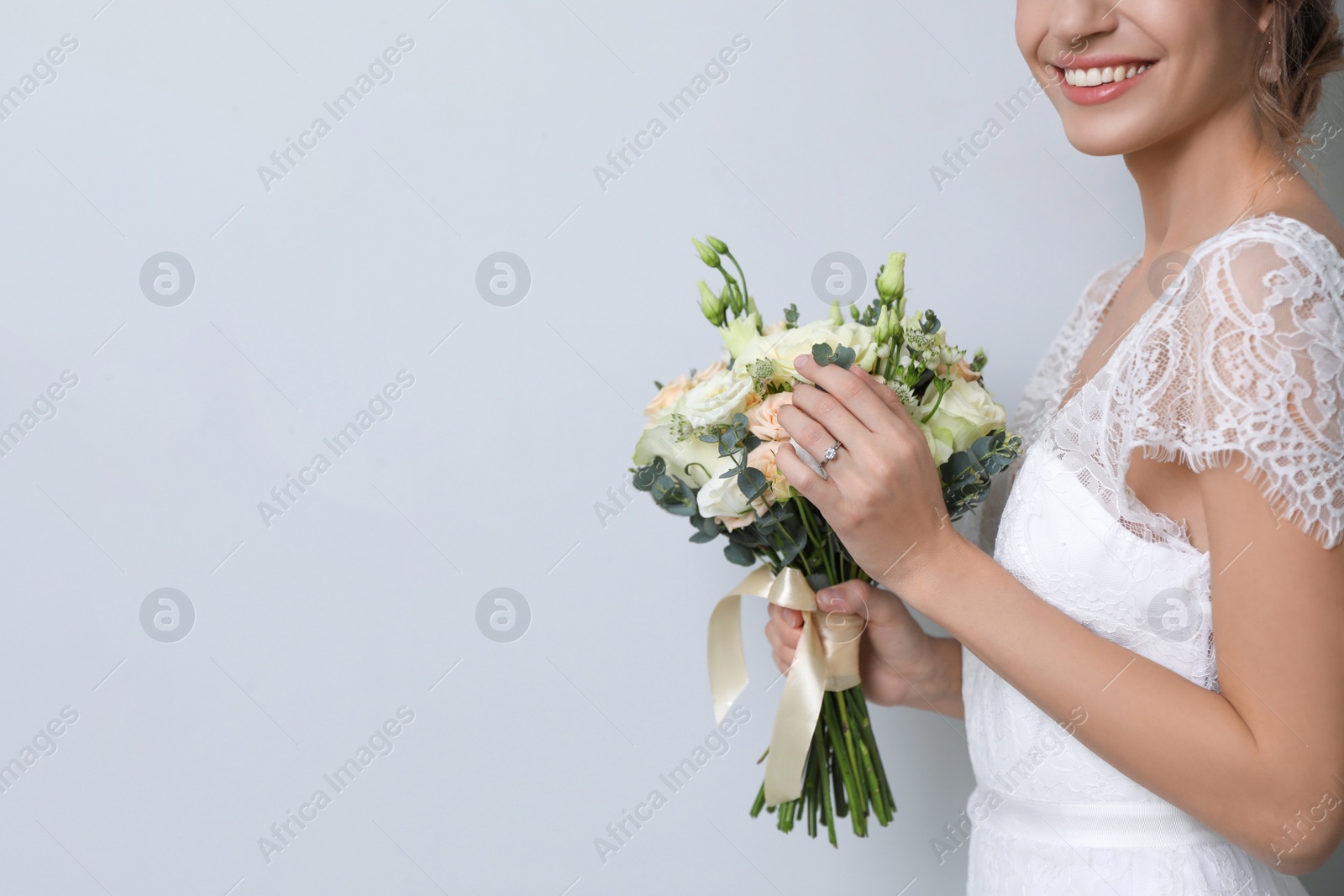 Photo of Young bride with beautiful wedding bouquet on light grey background, closeup. Space for text