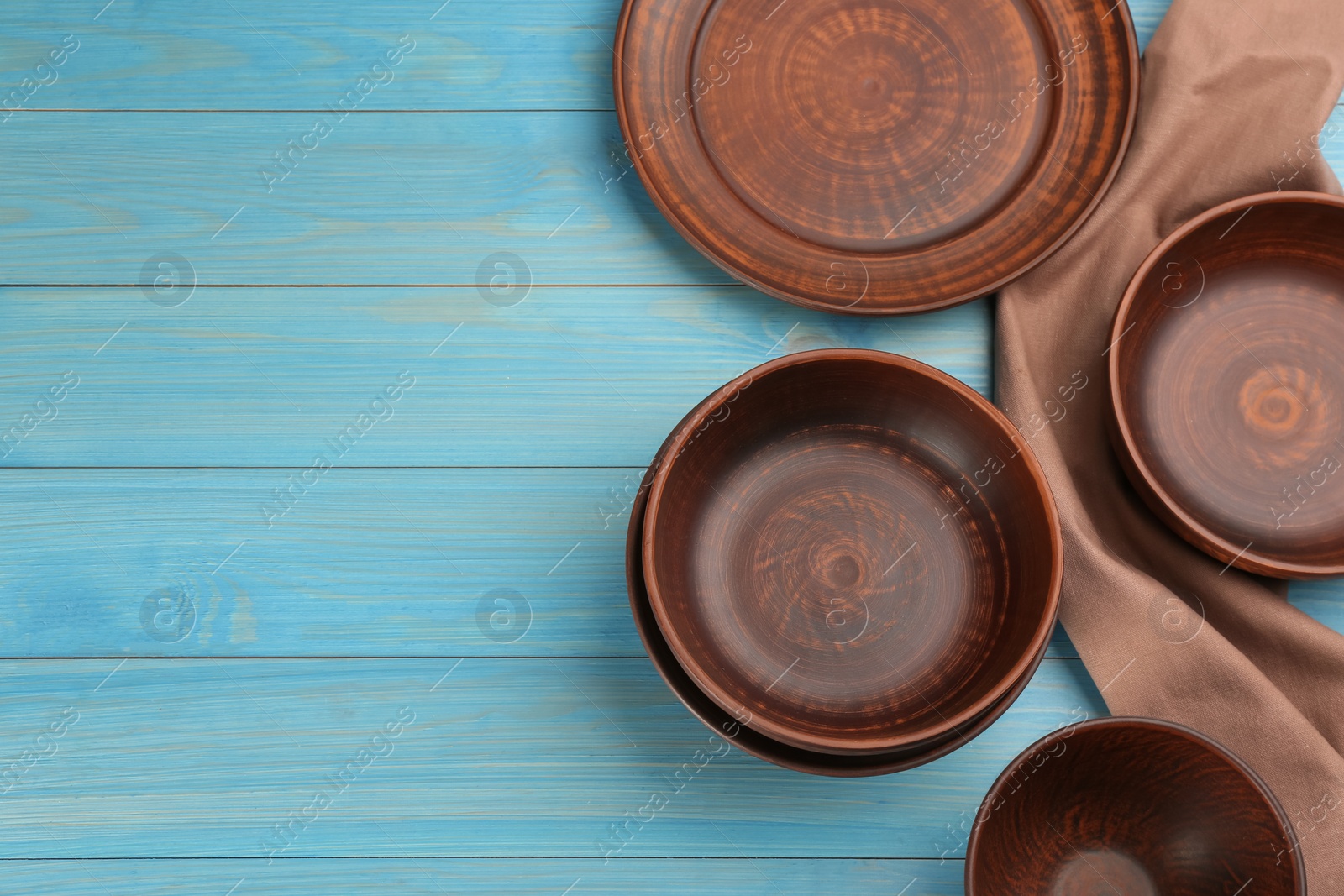 Photo of Set of clay utensils on light blue wooden table, flat lay. Space for text