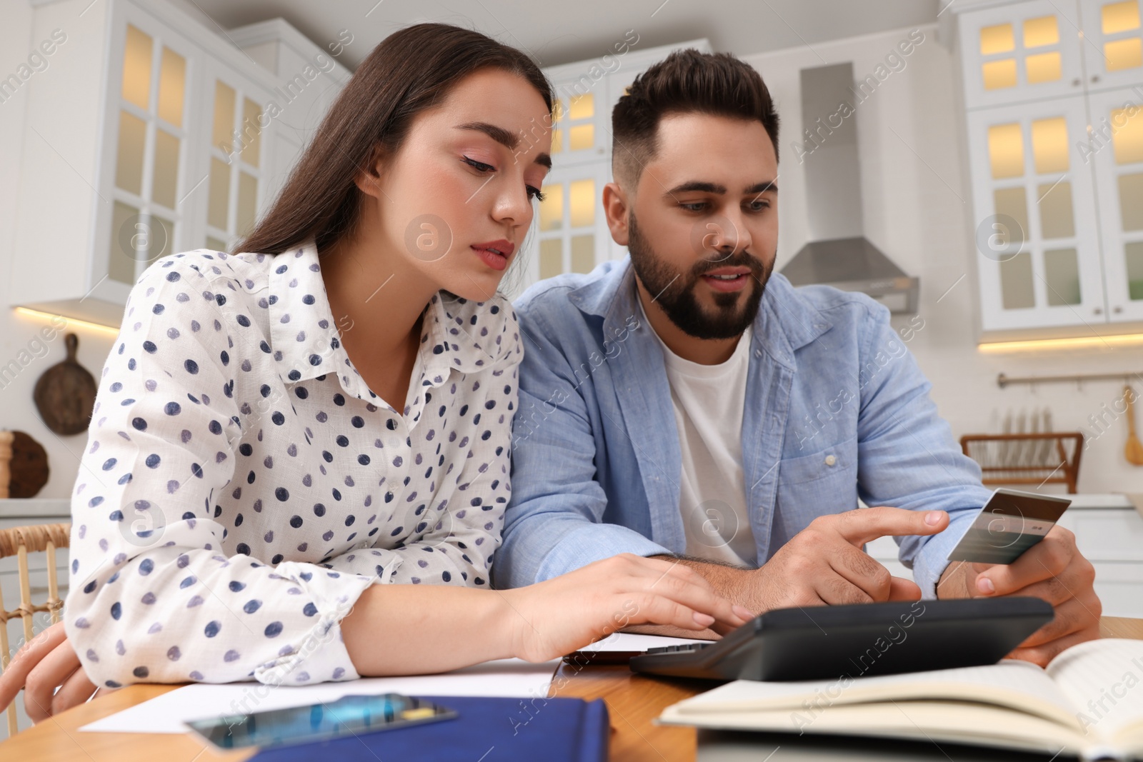 Photo of Young couple discussing family budget in kitchen