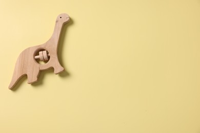 Baby accessory. Wooden rattle on yellow background, top view. Space for text