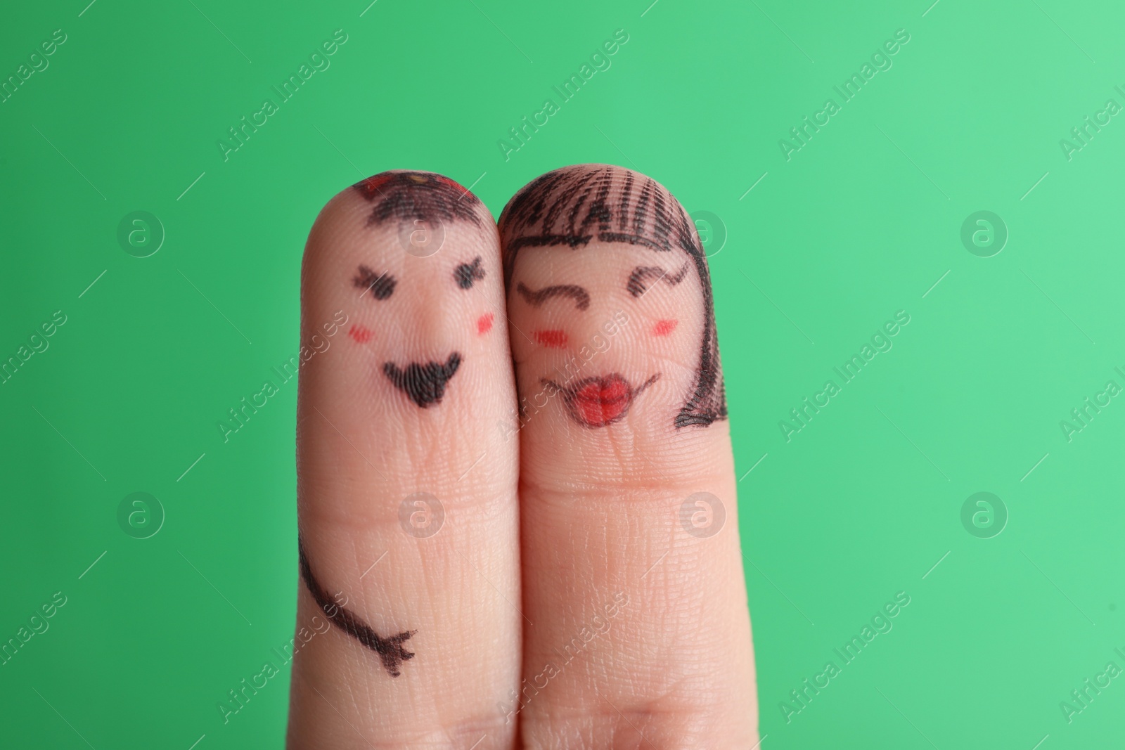 Photo of Two fingers with drawings of happy faces on green background. Spending time together