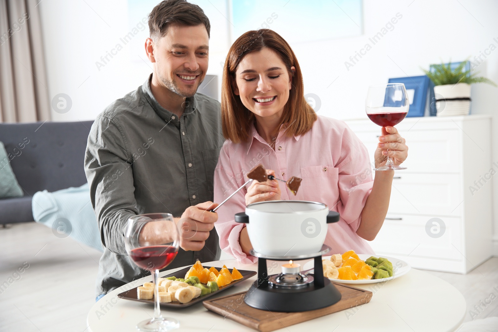 Photo of Happy couple enjoying fondue dinner at home