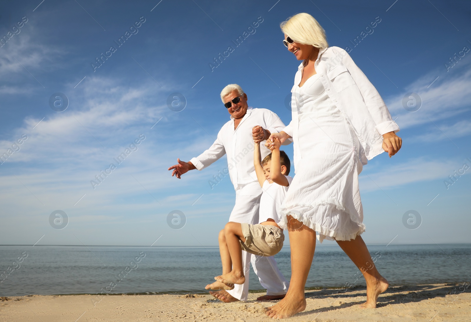 Photo of Cute little boy with grandparents spending time together on sea beach