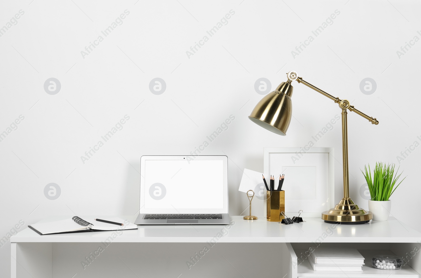 Photo of Cozy workspace with laptop, lamp and stationery on wooden desk at home