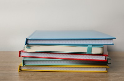 Photo of Stack of colorful planners on wooden table, closeup